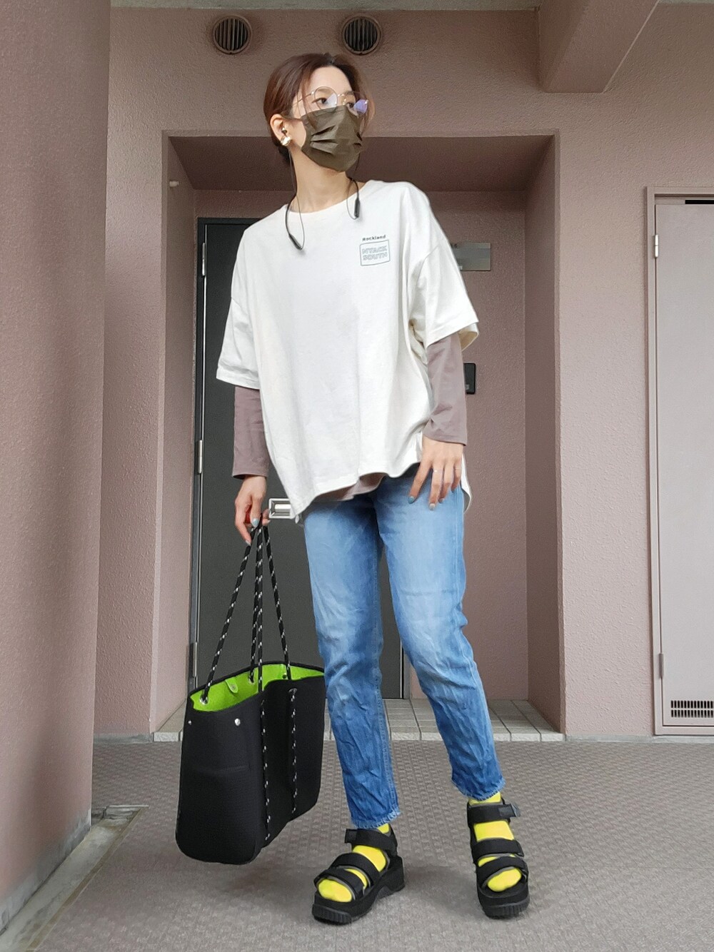 ブラック系のトートバッグ、ブルー系のデニムパンツ、ブラック系のサンダルを着用したレディースの春コーディネートの1枚目の写真