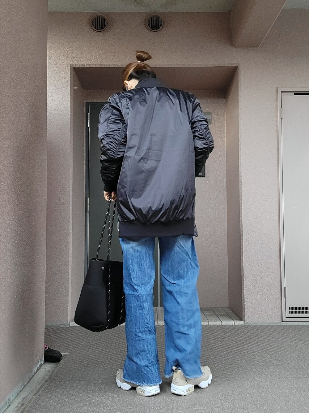 ブルー系のデニムパンツ、ベージュ系のスニーカー、ブラック系のトートバッグを着用したレディースの冬コーディネートの3枚目の写真