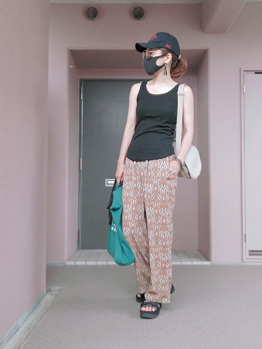 オレンジ系のその他パンツ、ベージュ系のショルダーバッグ、ブラック系のキャップを着用したレディースの夏コーディネートの1枚目の写真