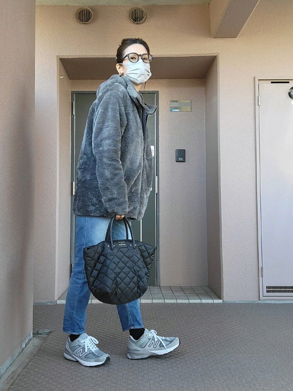 ブルー系のデニムパンツ、ブラック系のトートバッグ、グレー系のスニーカーを着用したレディースの冬コーディネートの1枚目の写真