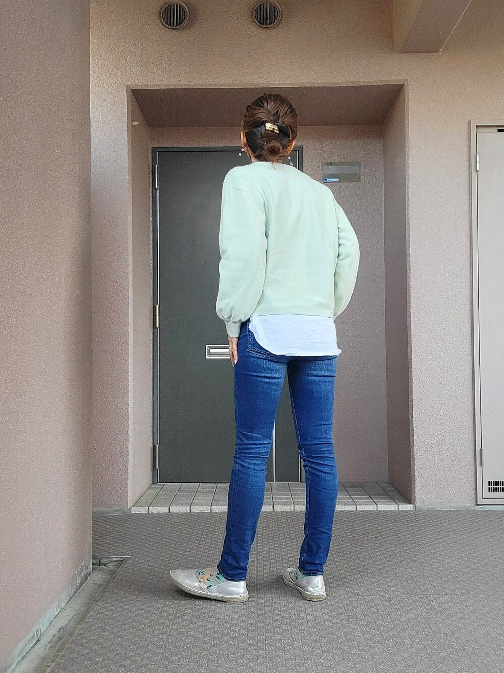 グリーン系のニット/セーター、ブルー系のデニムパンツ、シルバー系のスリッポンを着用したレディースの春コーディネートの2枚目の写真
