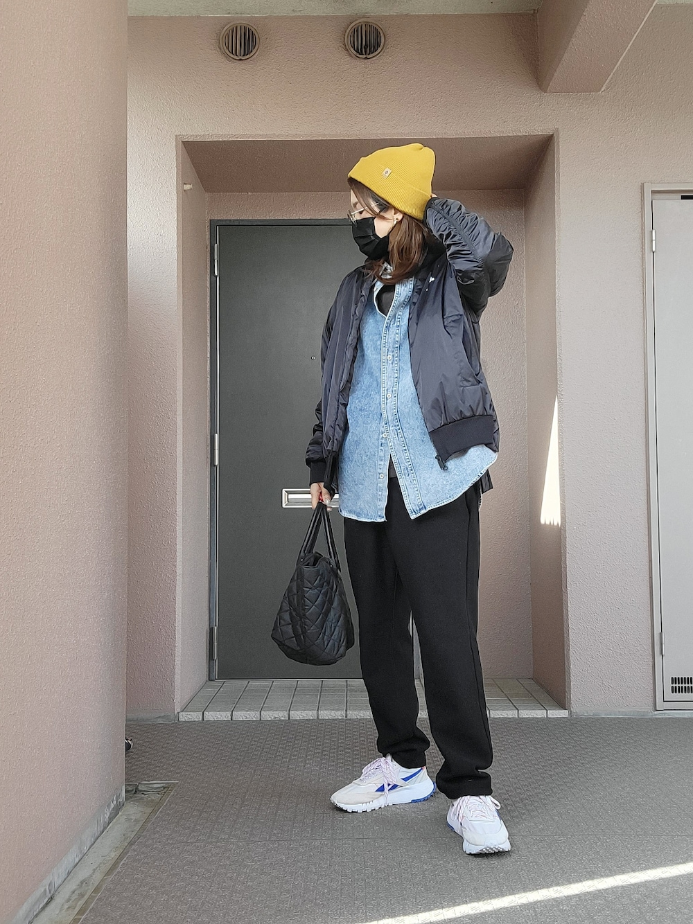 ブラック系のパンツ、ブラック系のトートバッグ、グレー系のスニーカーを着用したレディースの春コーディネートの2枚目の写真