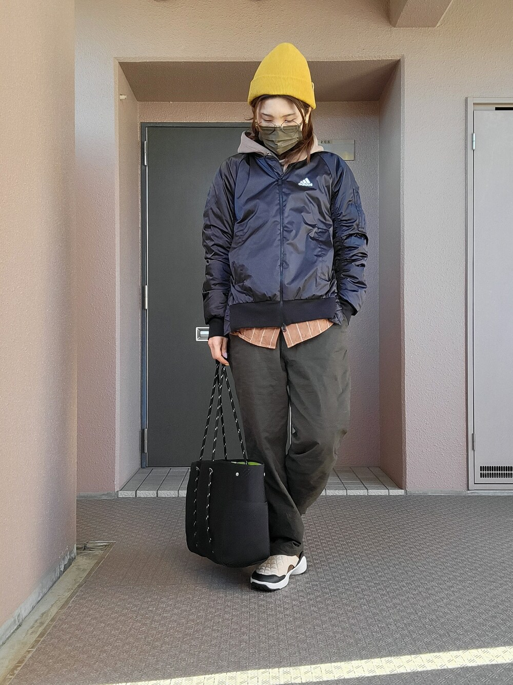 グリーン系のチノパンツ、ベージュ系のスリッポン、ブラック系のその他アウターを着用したレディースの冬コーディネートの3枚目の写真