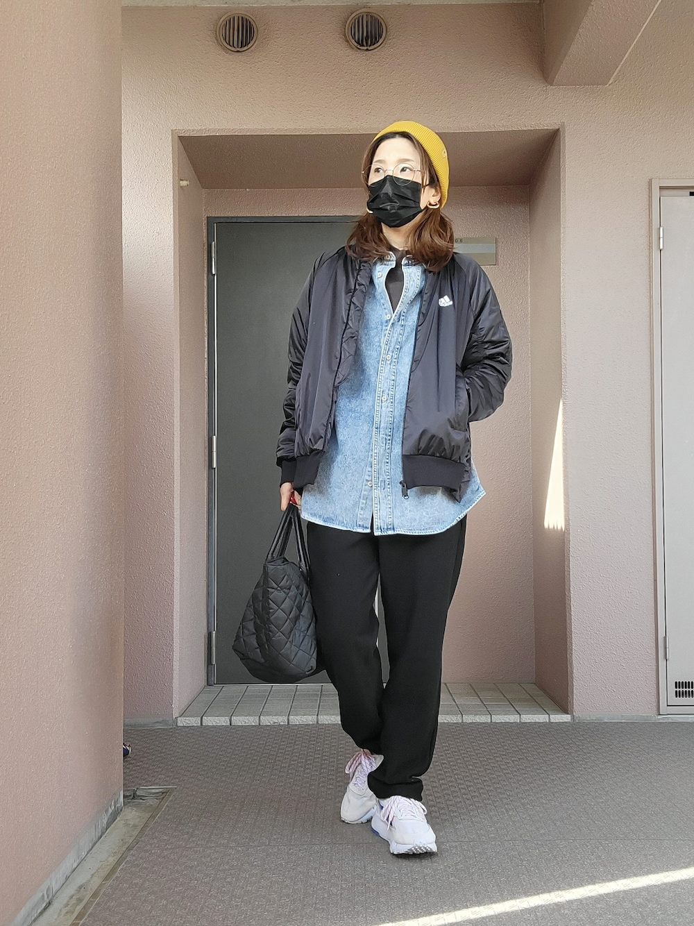 ブラック系のパンツ、ブラック系のトートバッグ、グレー系のスニーカーを着用したレディースの春コーディネートの3枚目の写真