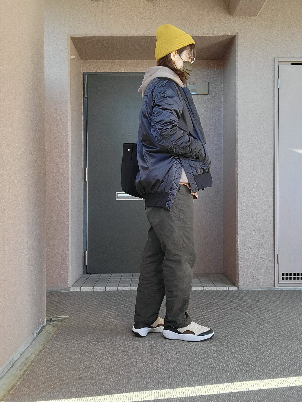 グリーン系のチノパンツ、ベージュ系のスリッポン、ブラック系のその他アウターを着用したレディースの冬コーディネートの4枚目の写真