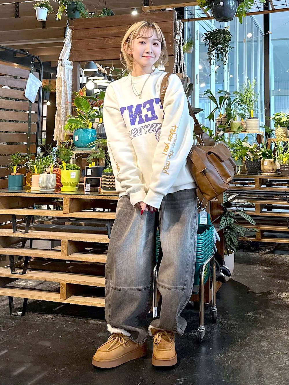 ブラウン系のデニムパンツ、イエロー系のモカシン/デッキシューズ、ブラウン系のショルダーバッグを着用したレディースの秋コーディネートの1枚目の写真