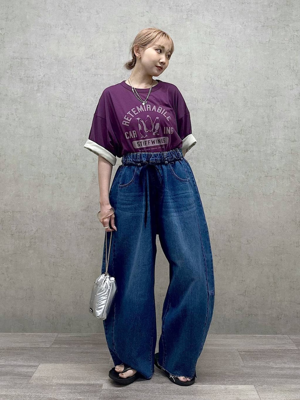 シルバー系のショルダーバッグ、パープル系のTシャツ/カットソー、ブルー系のデニムパンツを着用したレディースの春コーディネートの1枚目の写真