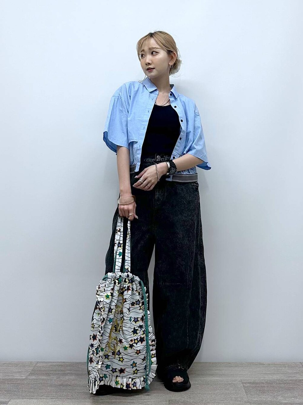 ブラック系のサンダル、ホワイト系のトートバッグ、ブラック系のデニムパンツを着用したレディースの夏コーディネートの1枚目の写真