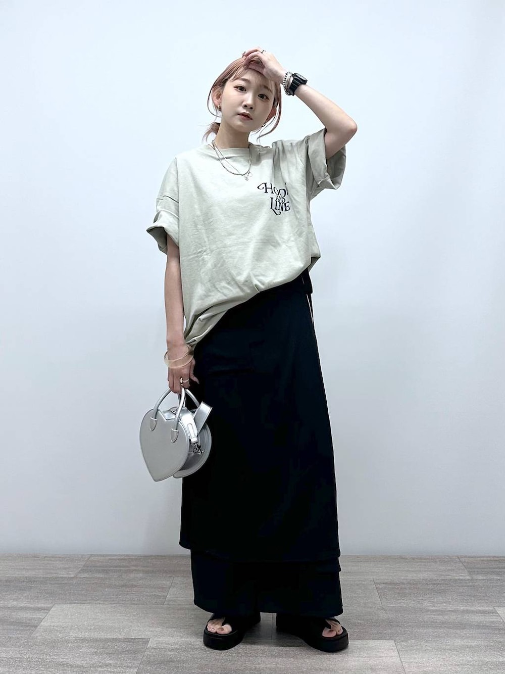 シルバー系のショルダーバッグ、ベージュ系のTシャツ/カットソー、ブラック系のサンダルを着用したレディースの夏コーディネートの1枚目の写真