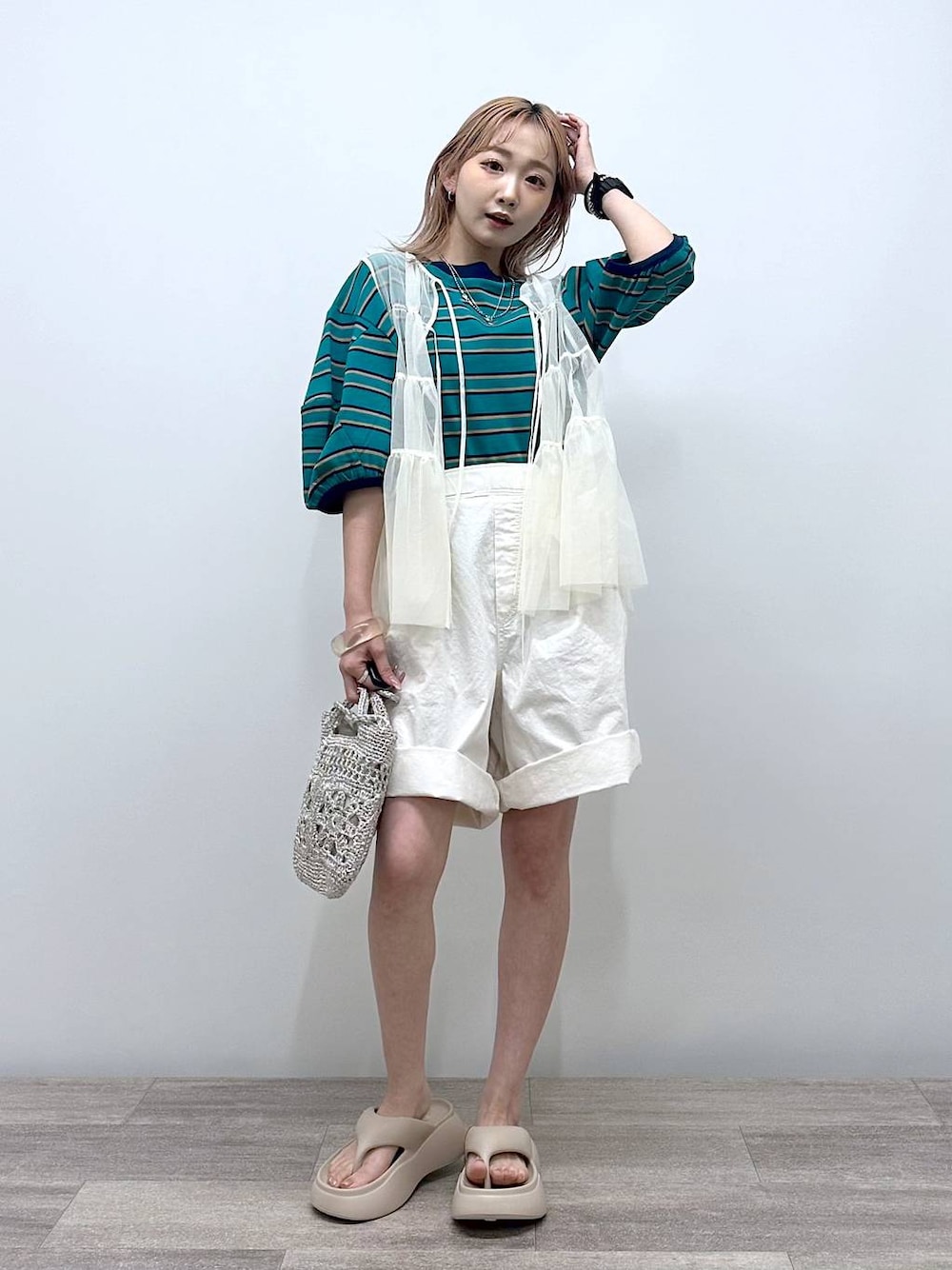 グレー系のショルダーバッグ、ベージュ系のサンダル、グリーン系のTシャツ/カットソーを着用したレディースの夏コーディネートの1枚目の写真