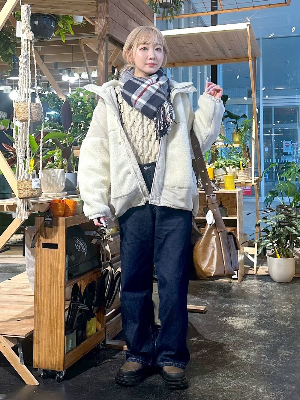 ベージュ系のブルゾン、ブルー系のデニムパンツ、ブラウン系のブーツを着用したレディースの冬コーディネートの1枚目の写真