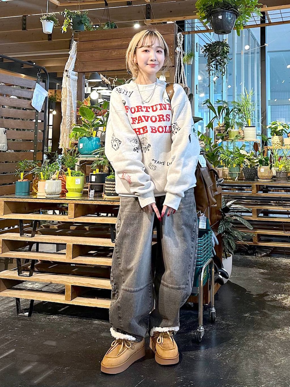ブラウン系のデニムパンツ、イエロー系のモカシン/デッキシューズ、ブラウン系のショルダーバッグを着用したレディースの秋コーディネートの1枚目の写真