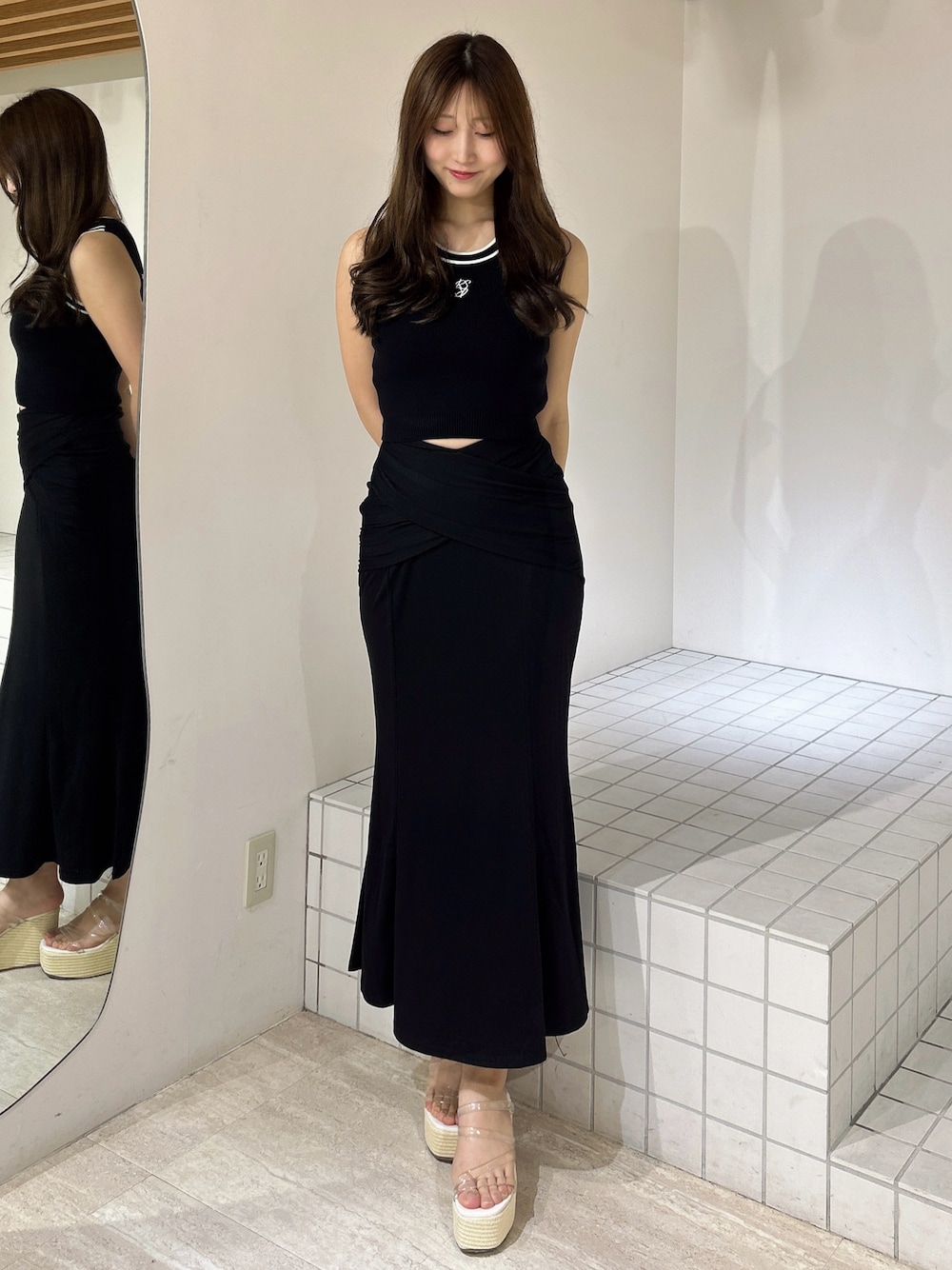 ブラック系のスカート、ホワイト系のサンダル、ブラック系のタンクトップを着用したレディースの夏コーディネートの1枚目の写真