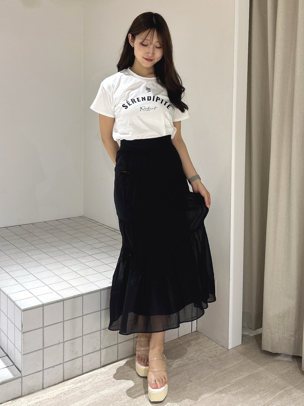 ブラック系のスカート、ホワイト系のTシャツ/カットソー、ホワイト系のサンダルを着用したレディースの夏コーディネートの1枚目の写真