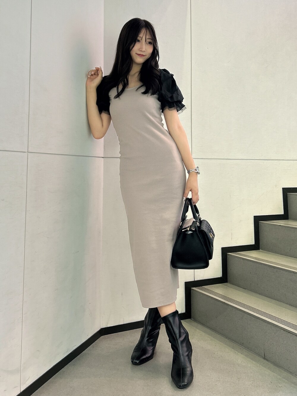 ベージュ系のワンピース、ブラック系のハンドバッグを着用したレディースの秋コーディネートの1枚目の写真