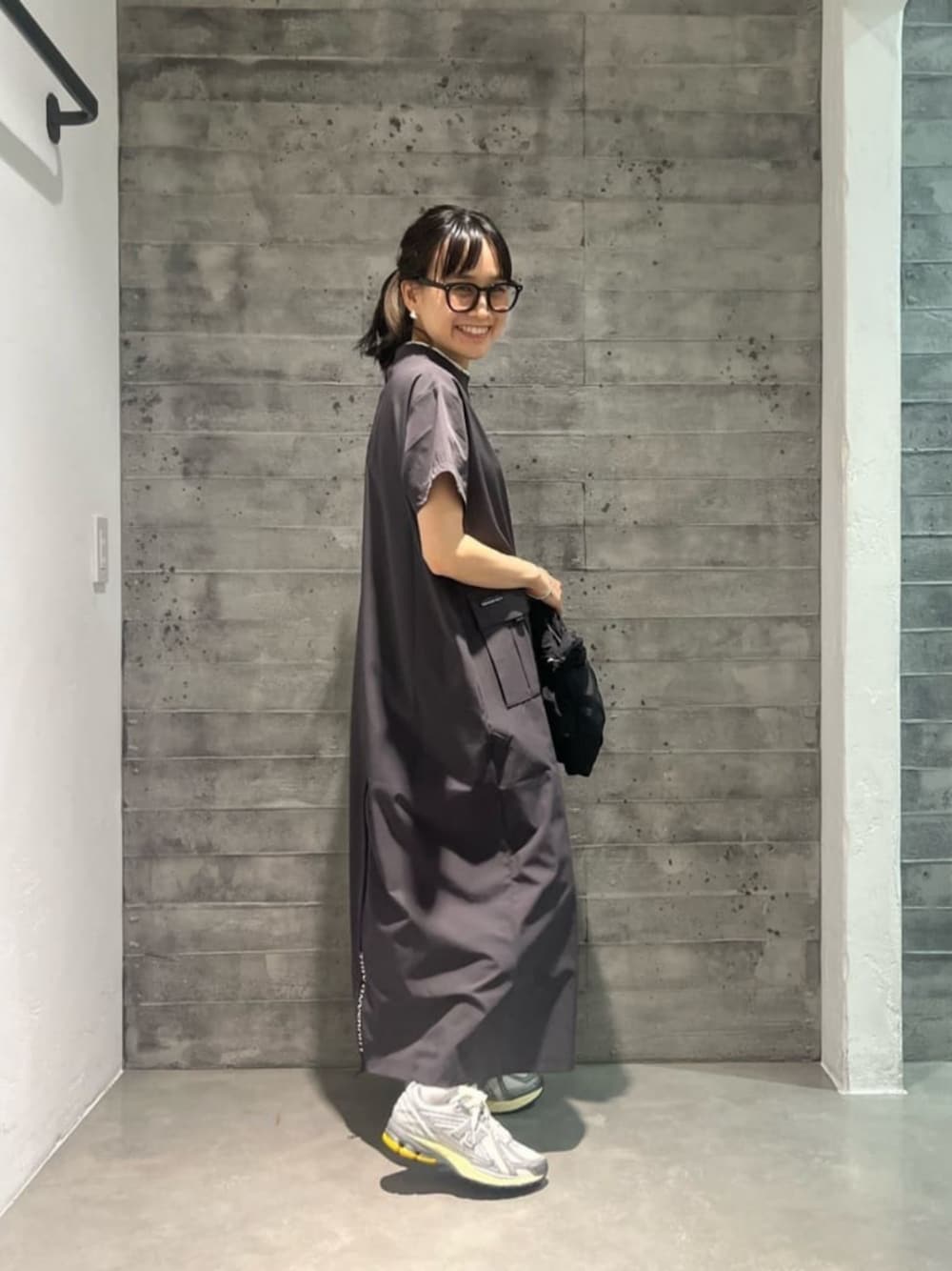 グレー系のワンピース、グレー系のスニーカー、ブラック系のショルダーバッグを着用したレディースの夏コーディネートの1枚目の写真