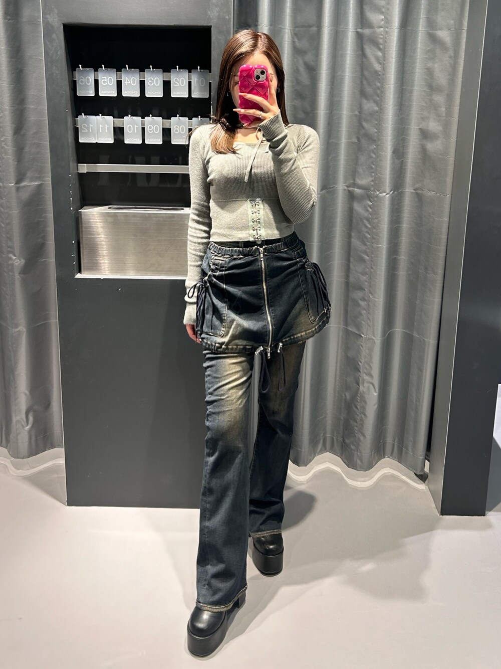 グレー系のニット/セーター、ブルー系のデニムパンツ、ブラック系のブーツを着用したレディースの秋コーディネートの1枚目の写真