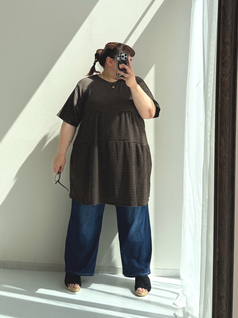 ブルー系のパンツ、ブラック系のサンダル、ブラウン系のチュニックを着用したレディースの春コーディネートの1枚目の写真