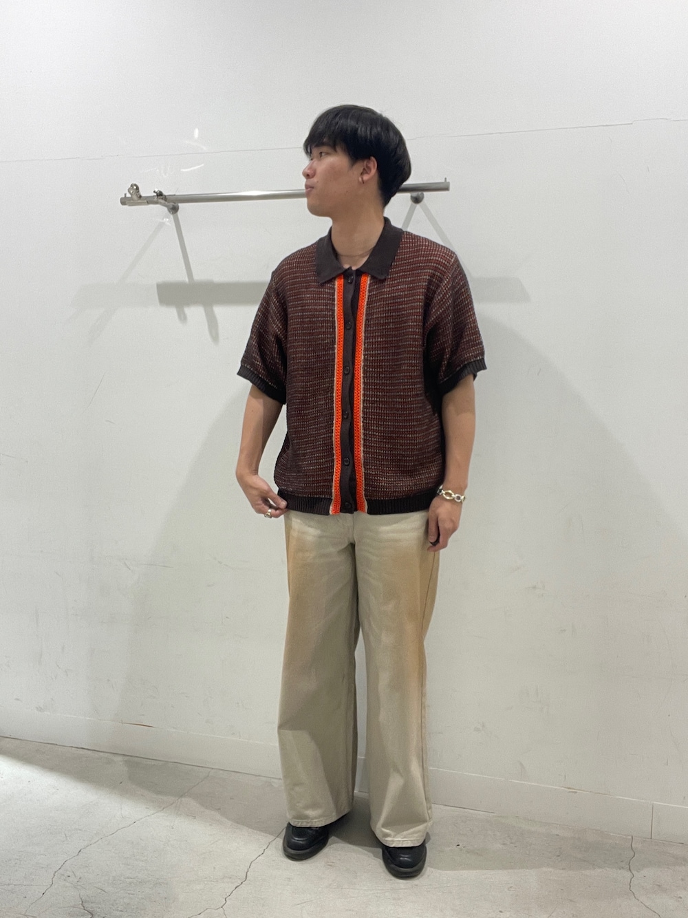 レッド系のニット/セーター、グリーン系のデニムパンツを着用したメンズの春コーディネートの1枚目の写真