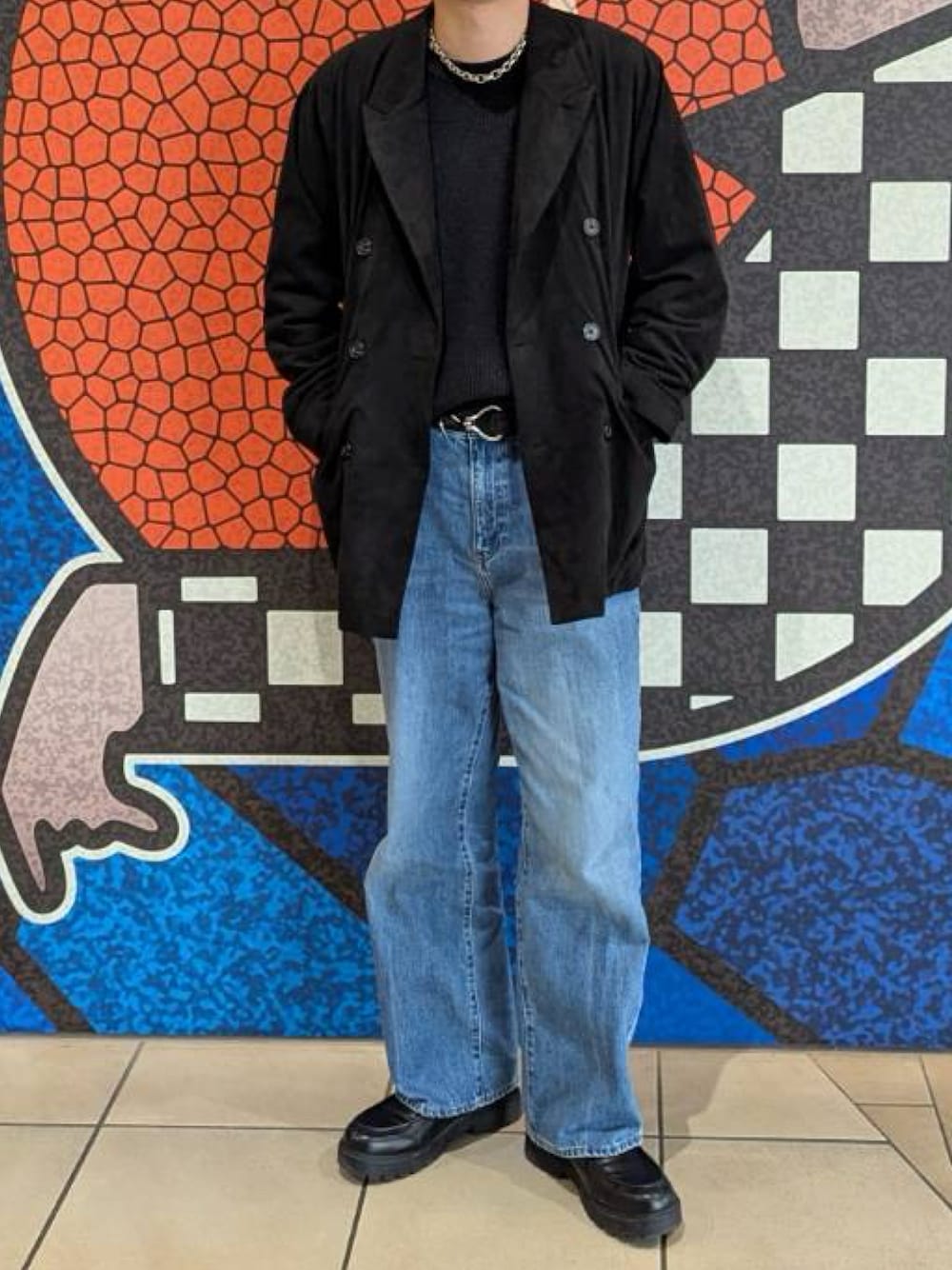 ブラック系のテーラードジャケット、グレー系のニット/セーター、ブルー系のデニムパンツを着用したメンズの冬コーディネートの1枚目の写真