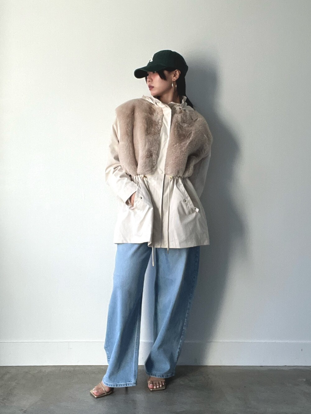 ベージュ系のブルゾン、ブルー系のデニムパンツ、グリーン系のキャップを着用したレディースの秋コーディネートの1枚目の写真