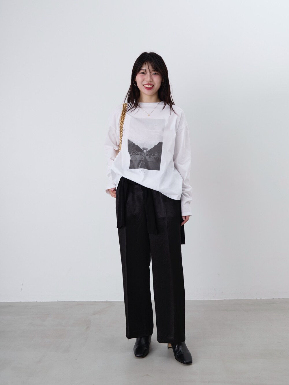 ベージュ系のショルダーバッグ、ホワイト系のTシャツ/カットソー、ブラック系のカーディガン/ボレロを着用したレディースの冬コーディネートの1枚目の写真