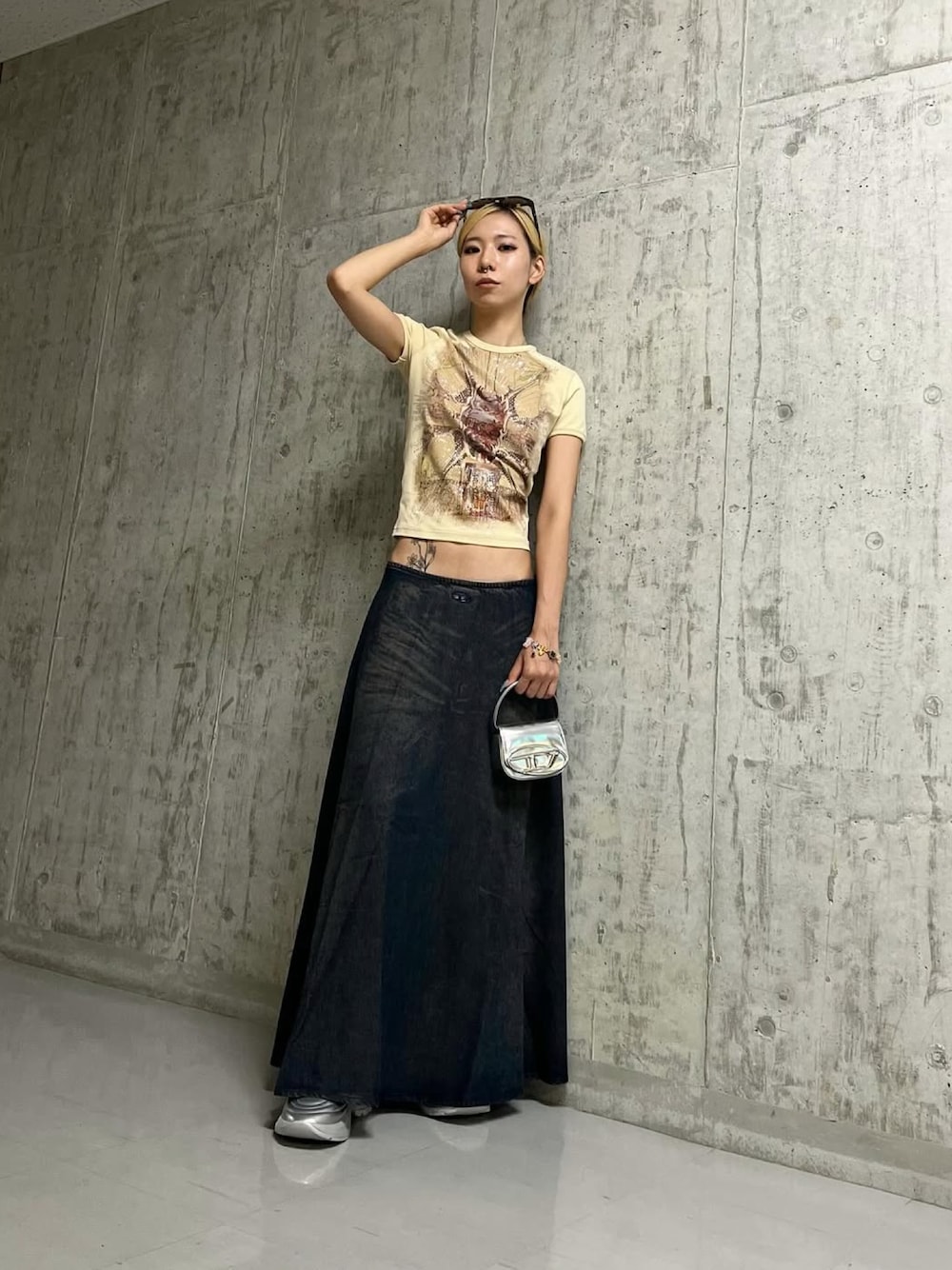 ブルー系のデニムスカート、シルバー系のショルダーバッグ、シルバー系のスニーカーを着用したレディースの夏コーディネートの1枚目の写真