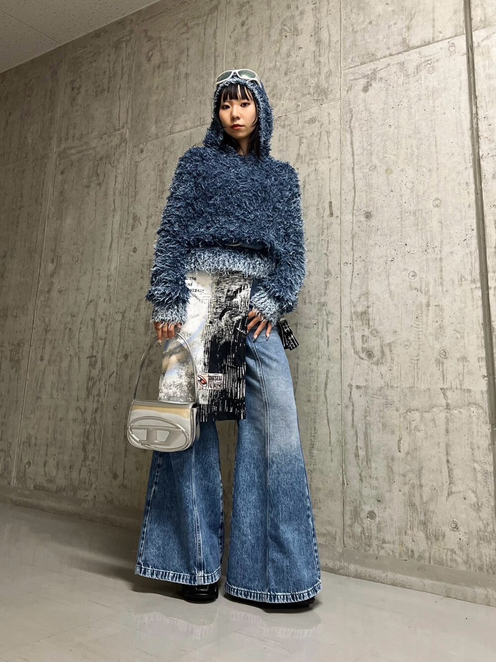 シルバー系のショルダーバッグ、ブルー系のデニムパンツ、ブラック系のその他シューズを着用したレディースの秋コーディネートの1枚目の写真