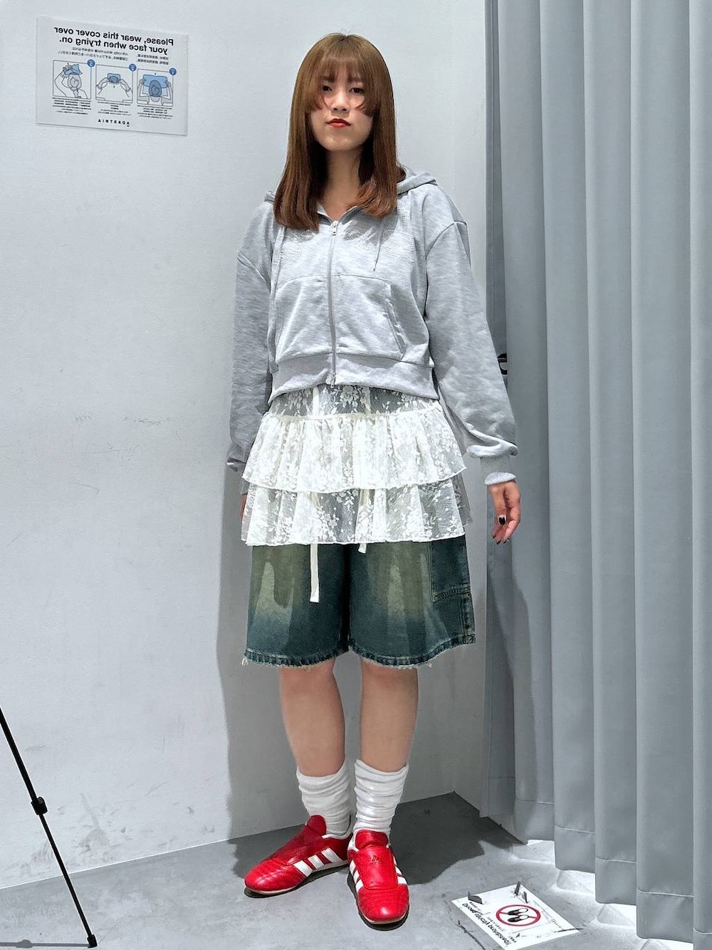 グレー系のパーカー、ホワイト系のワンピース、ブルー系のデニムパンツを着用したレディースの春コーディネートの1枚目の写真