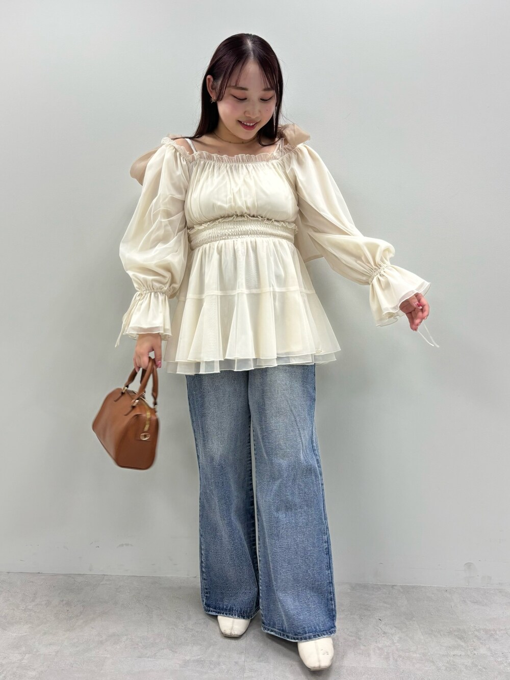 ブルー系のデニムパンツ、ホワイト系のシャツ/ブラウス、ブラウン系のボストンバッグを着用したレディースの春コーディネートの1枚目の写真