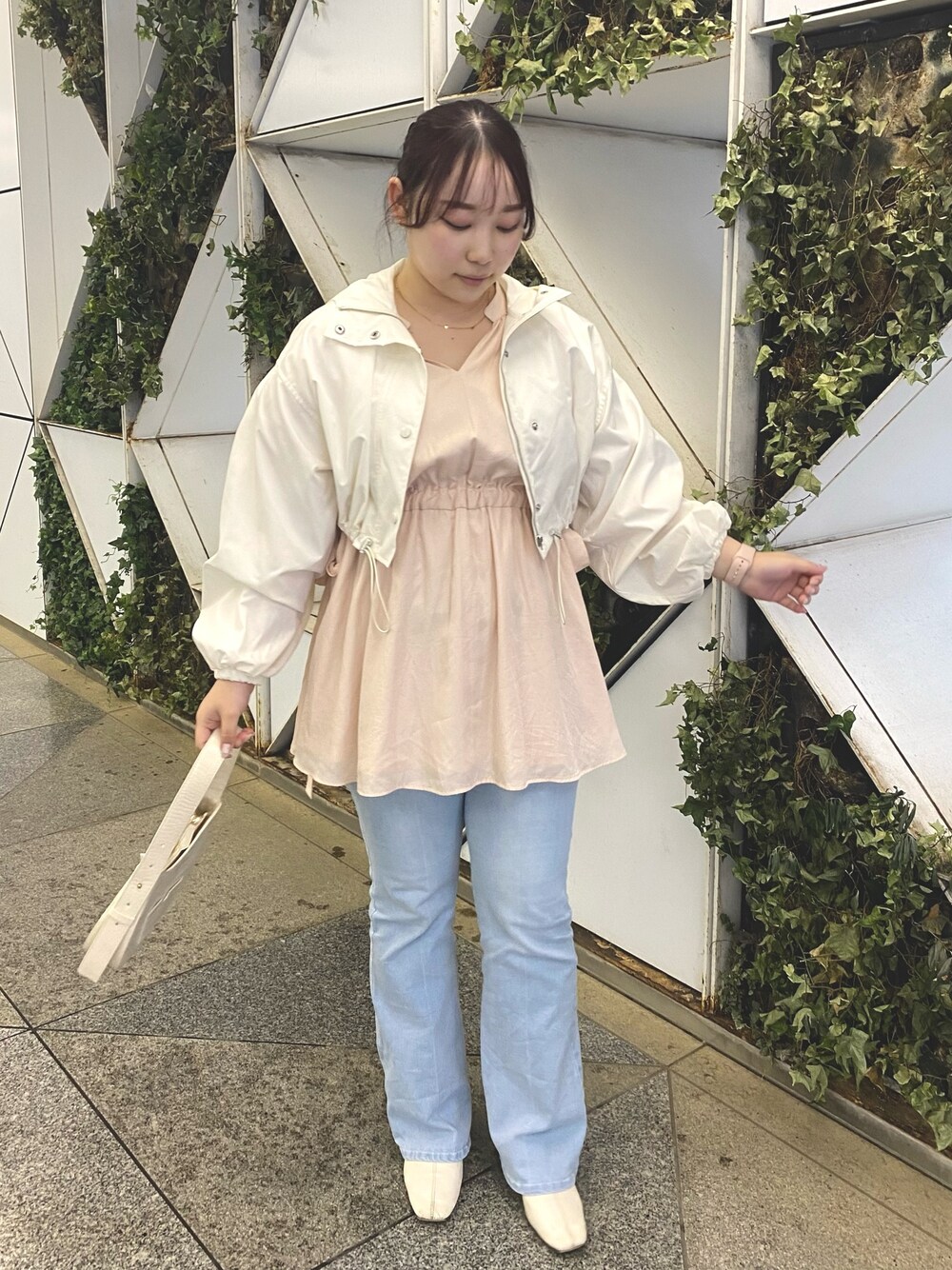 ピンク系のチュニック、ブルー系のデニムパンツ、ホワイト系のマウンテンパーカーを着用したレディースの春コーディネートの1枚目の写真