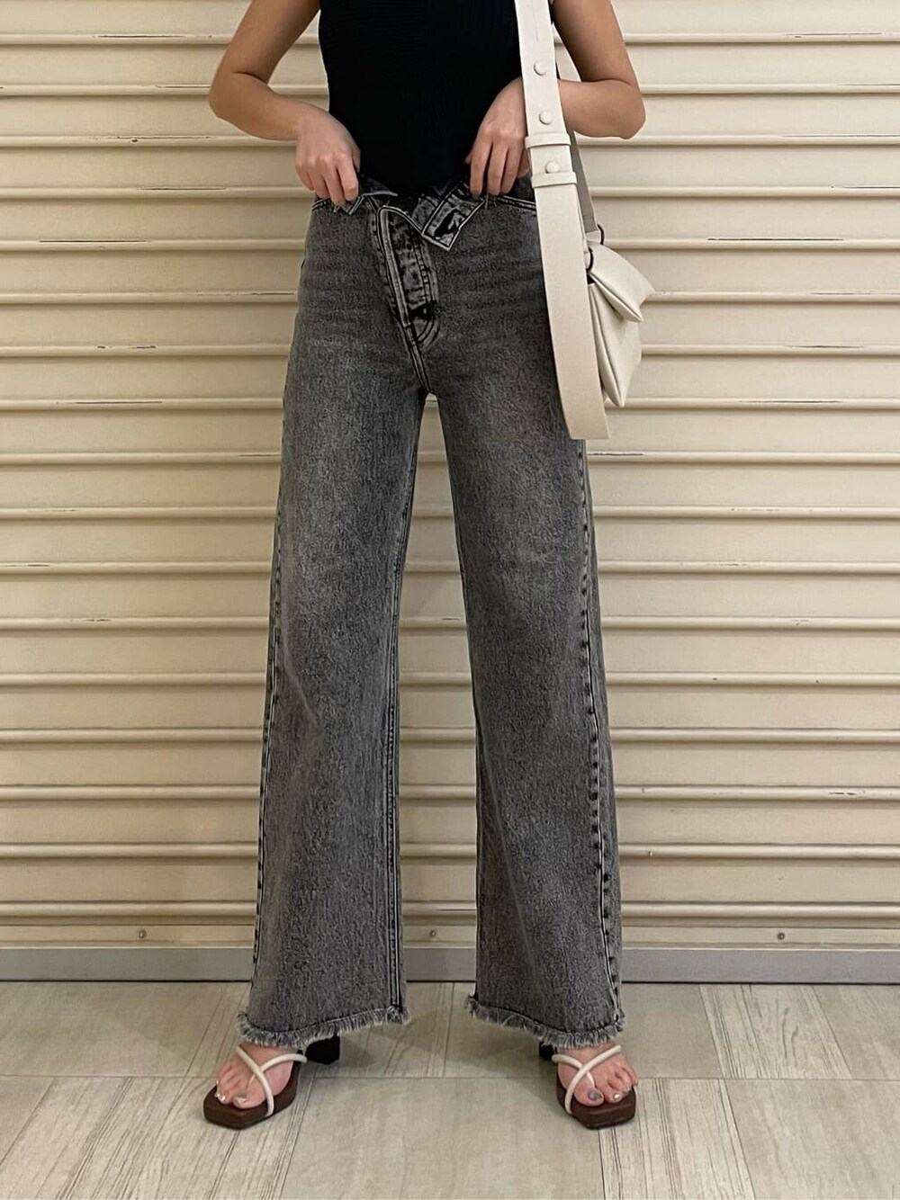 ホワイト系のショルダーバッグ、ホワイト系のサンダル、ブラック系のデニムパンツを着用したレディースの夏コーディネートの1枚目の写真