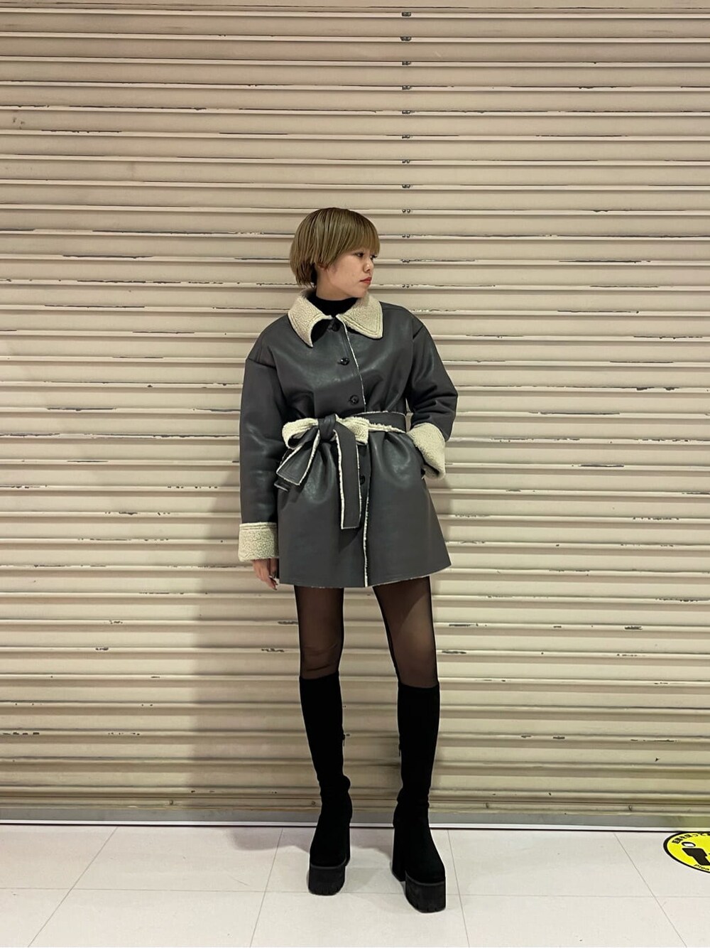 グレー系のムートンコート、ブラック系のブーツを着用したレディースの冬コーディネートの1枚目の写真