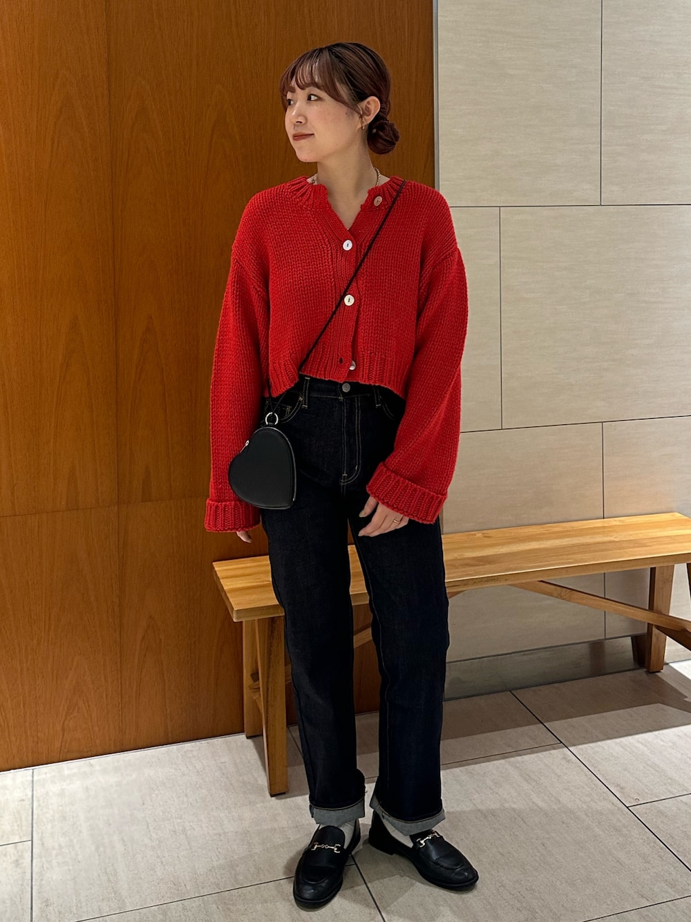 レッド系のカーディガン/ボレロ、ブルー系のデニムパンツ、ブラック系のショルダーバッグを着用したレディースの秋コーディネートの1枚目の写真