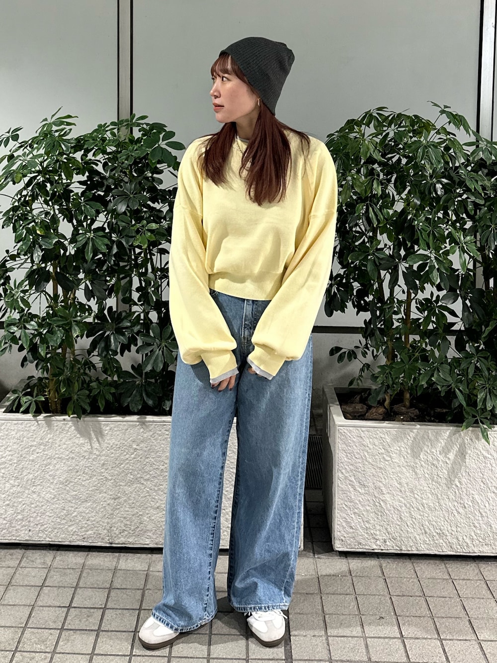 イエロー系のニット/セーター、ブルー系のデニムパンツ、グレー系のニットキャップ/ビーニーを着用したレディースの冬コーディネートの1枚目の写真