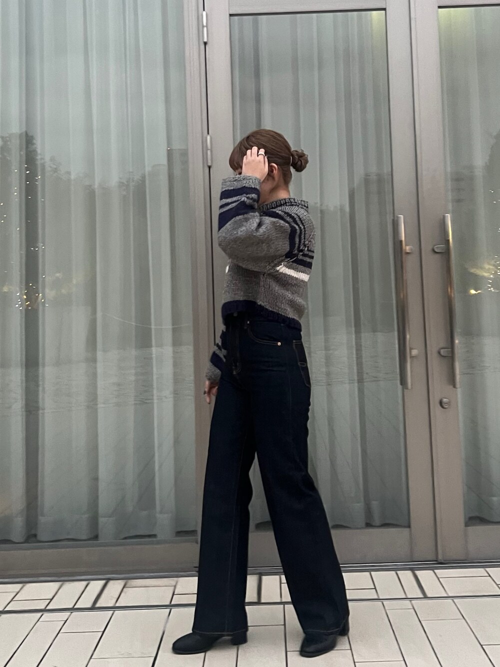 グレー系のニット/セーター、ブルー系のデニムパンツを着用したレディースの冬コーディネートの1枚目の写真