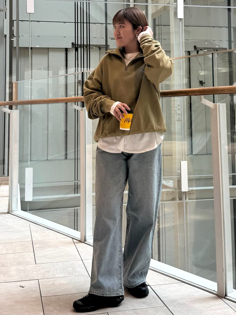 グリーン系のスウェット、ホワイト系のTシャツ/カットソー、ブルー系のデニムパンツを着用したレディースの冬コーディネートの1枚目の写真