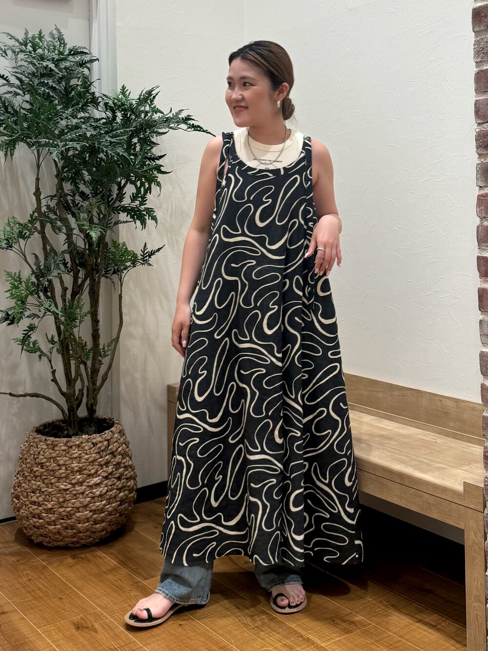 ホワイト系のタンクトップ、ブラック系のサンダル、ブルー系のデニムパンツを着用したレディースの夏コーディネートの1枚目の写真