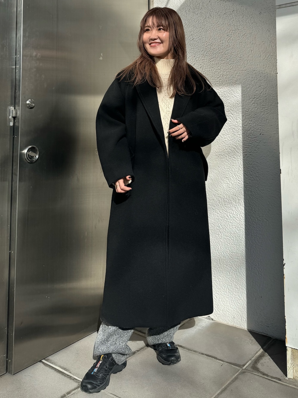 ホワイト系のニット/セーター、グレー系のその他パンツ、ブラック系のチェスターコートを着用したレディースの冬コーディネートの1枚目の写真