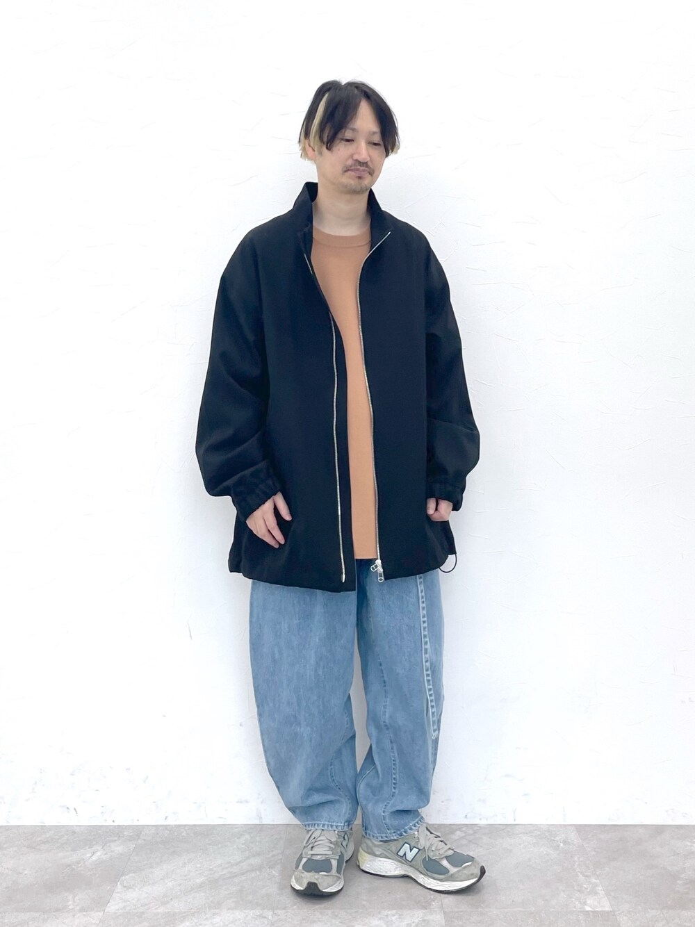 ブラック系のブルゾン、ベージュ系のトップス、ブルー系のデニムパンツを着用したメンズの冬コーディネートの1枚目の写真
