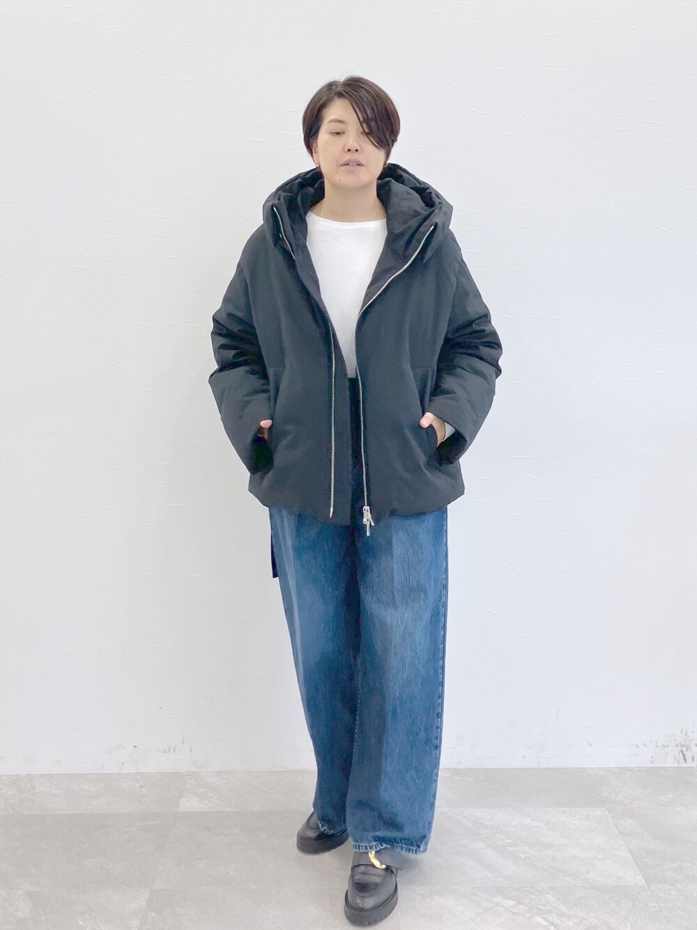 ブラック系のダウンジャケット/コート、ホワイト系のTシャツ/カットソー、ブルー系のデニムパンツを着用したレディースの秋コーディネートの1枚目の写真