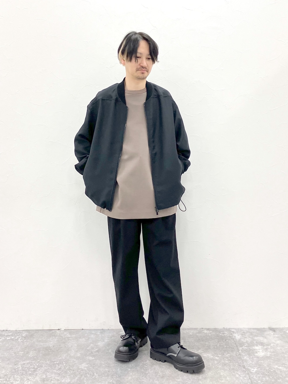 ブラック系のMA-1、ブラウン系のTシャツ/カットソー、ブラック系のスラックスを着用したメンズの春コーディネートの1枚目の写真