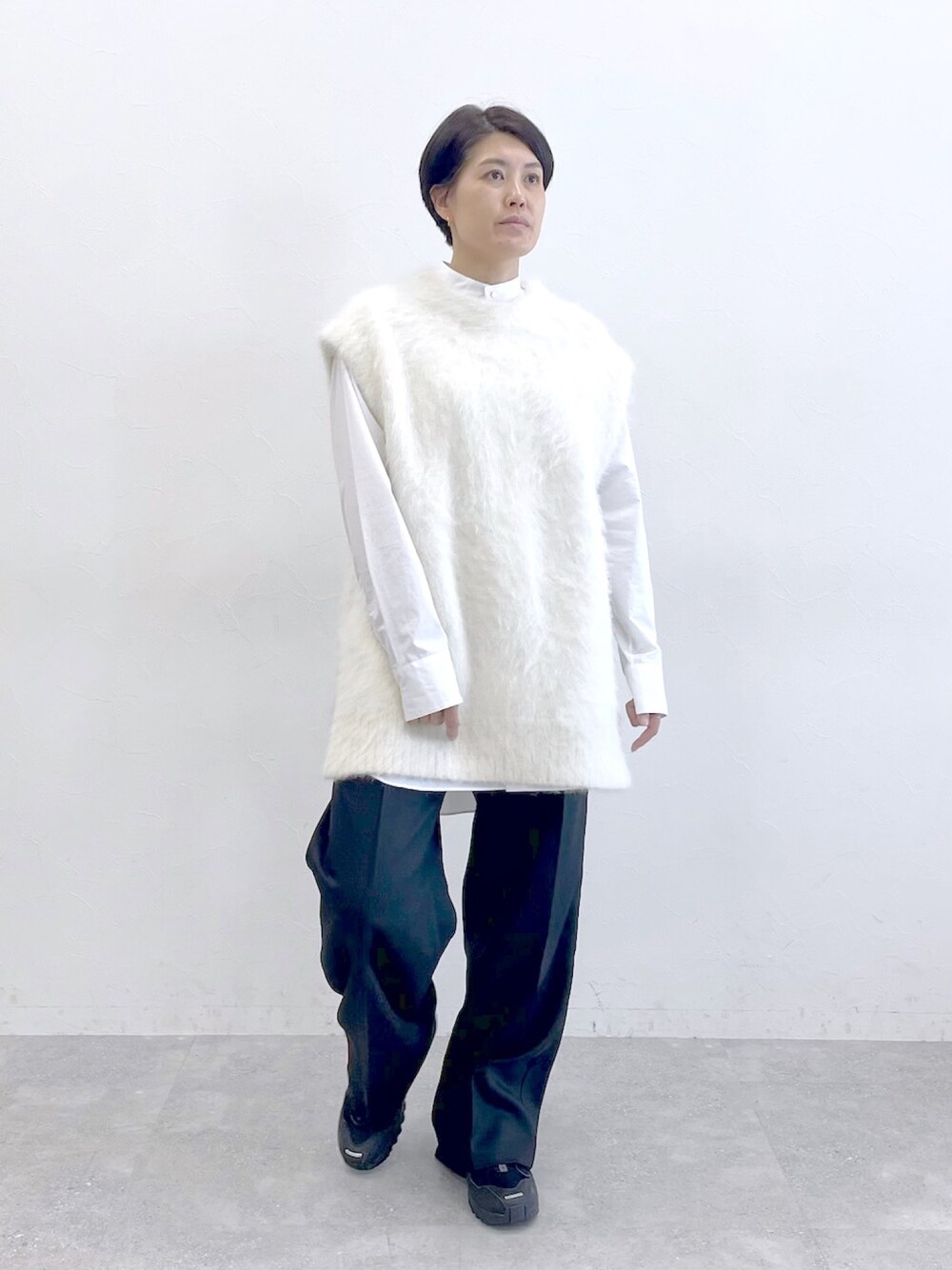 ホワイト系のニット/セーター、ホワイト系のシャツ/ブラウス、ブラック系のスラックスを着用したレディースの冬コーディネートの1枚目の写真
