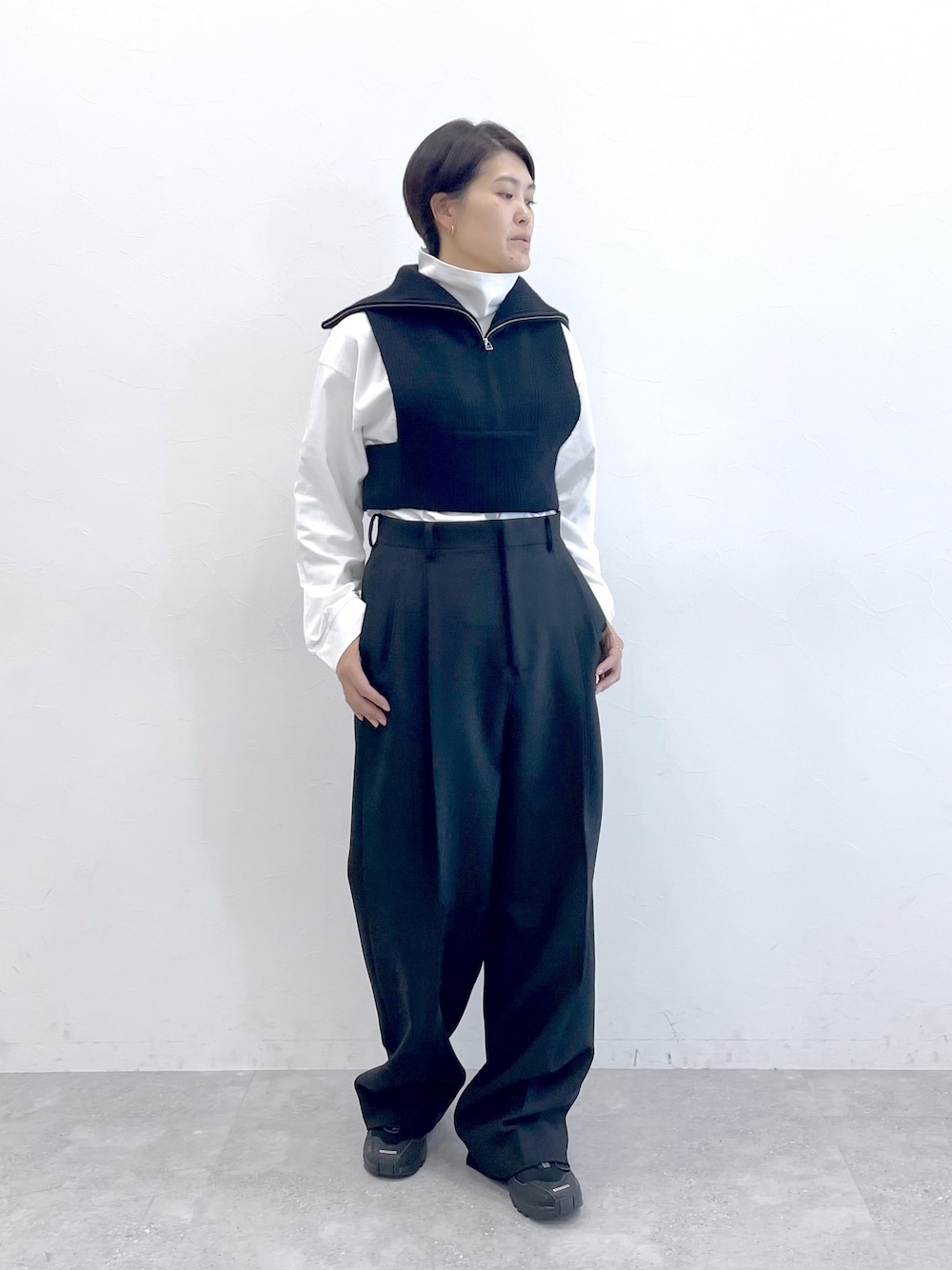 ブラック系のベスト、ホワイト系のTシャツ/カットソー、ブラック系のスラックスを着用したレディースの冬コーディネートの1枚目の写真