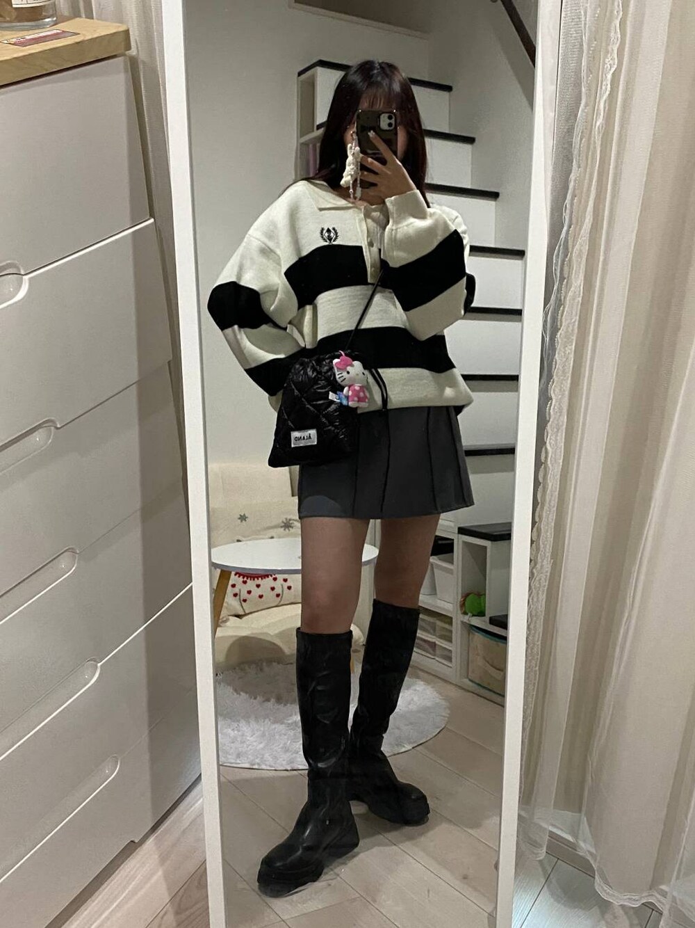 グレー系のスカート、ブラック系のショルダーバッグ、その他のニット/セーターを着用したレディースの春コーディネートの1枚目の写真