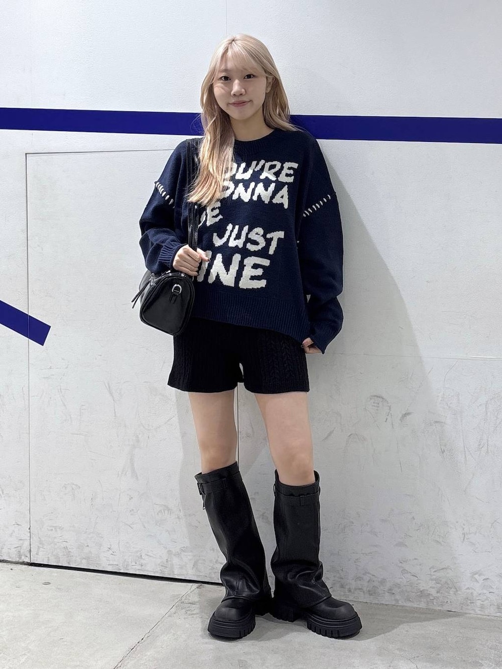 ブラック系のハンドバッグ、ブラック系のブーツ、ブルー系のニット/セーターを着用したレディースの秋コーディネートの1枚目の写真