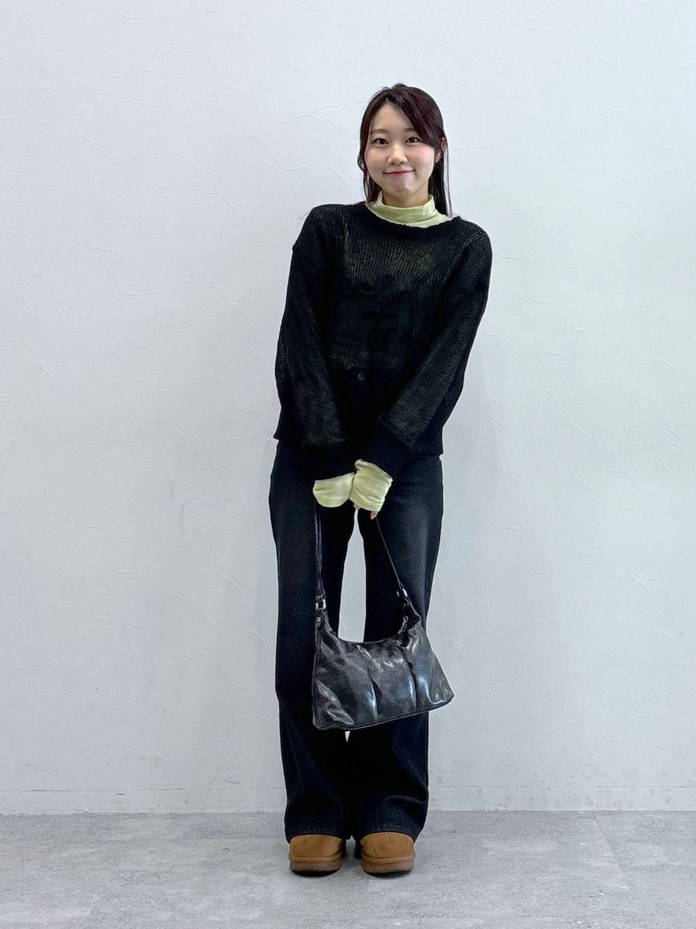 ブラック系のデニムパンツ、ブラック系のハンドバッグ、グリーン系のTシャツ/カットソーを着用したレディースの冬コーディネートの1枚目の写真