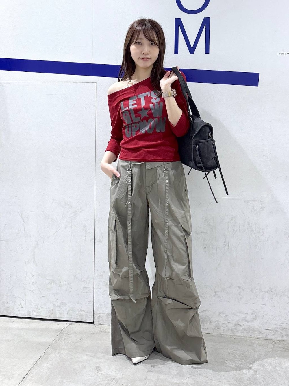 グリーン系のカーゴパンツ、ホワイト系のパンプス、ブラック系のショルダーバッグを着用したレディースの秋コーディネートの1枚目の写真