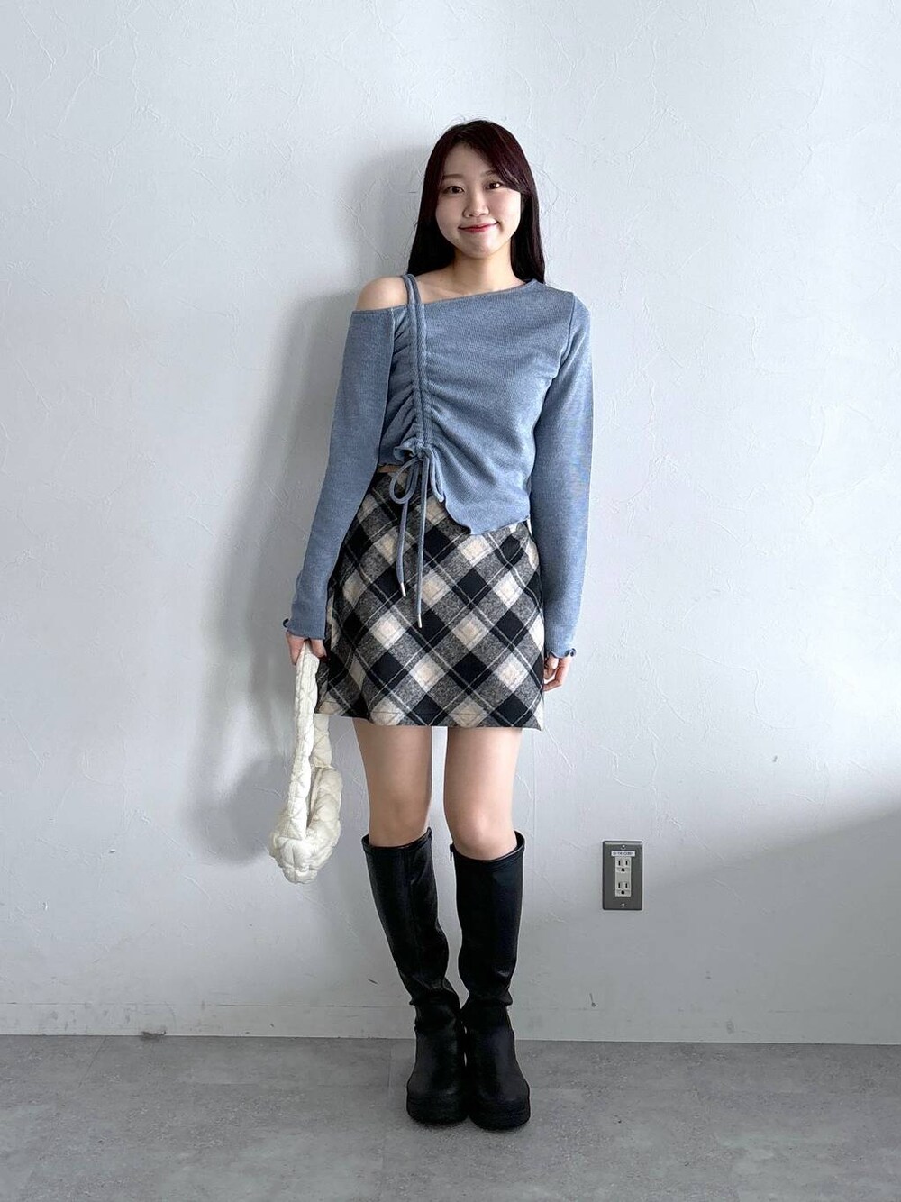 ホワイト系のショルダーバッグ、ブラック系のスカート、ブルー系のTシャツ/カットソーを着用したレディースの冬コーディネートの1枚目の写真