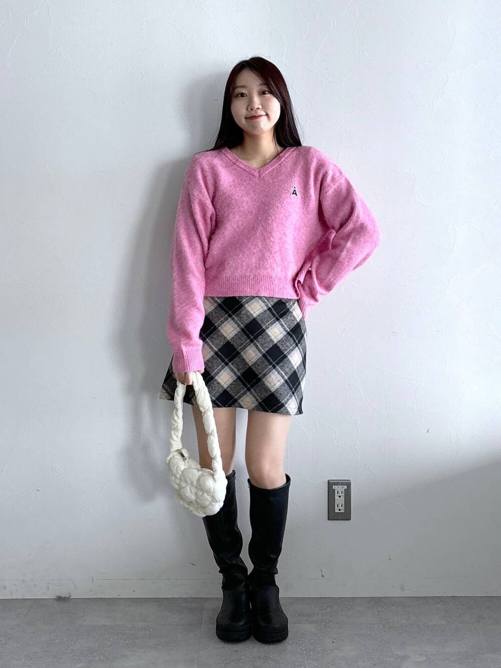 ホワイト系のショルダーバッグ、ブラック系のスカート、ピンク系のニット/セーターを着用したレディースの冬コーディネートの1枚目の写真